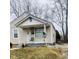Single-story home features light siding, covered porch with a small chair, and minimal front yard landscaping at 620 W Madison St, Alexandria, IN 46001