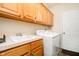 A well-lit laundry room with a sink, wooden cabinets, washer, and dryer at 6528 Hedback Dr, Indianapolis, IN 46220