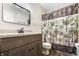 Neutral bathroom with wood vanity, mirror, and shower with a palm tree shower curtain at 7463 Pebblebrooke W Dr, Indianapolis, IN 46236