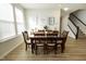 Well-lit dining area featuring a dark wood table, six chairs, and stylish decor, with stairs in the background at 761 Stone Trace Ct, Avon, IN 46123