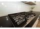 Close-up of a modern gas cooktop with white subway tile backsplash and sleek black countertops at 761 Stone Trace Ct, Avon, IN 46123