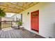 Inviting front porch with a rocking chair, wooden deck, and a vibrant red door at 7859 Moore Rd, Gosport, IN 47433