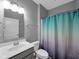 Bathroom featuring a shower with blue and purple curtain, toilet and sink with gray cabinets at 8727 Faulkner Dr, Indianapolis, IN 46239
