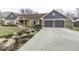 This home features a brick facade, an attached garage, manicured bushes, and a long driveway at 8901 Rocky Ridge Rd, Indianapolis, IN 46217