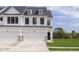 Modern townhome featuring a white facade, black trim, a two-car garage and well-manicured lawn at 10959 Morab Dr, Zionsville, IN 46077