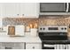 Modern kitchen showcasing stainless steel appliances, white cabinetry, quartz countertop, and tile backsplash at 11866 Weathered Edge Dr, Fishers, IN 46037