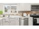 Well-lit kitchen featuring white cabinets, stainless steel appliances, and a charming mosaic tile backsplash at 11866 Weathered Edge Dr, Fishers, IN 46037