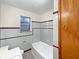 Well-lit bathroom featuring tiled walls, bathtub and shower combo, and a large window at 1221 Kessler Blvd E Dr, Indianapolis, IN 46220
