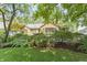 A well-maintained front yard featuring mature trees, lush greenery, and a brick home facade at 14 Kessler Blvd W Dr, Indianapolis, IN 46208