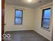 A basic empty room with gray floors, two windows, and white paneled walls at 1900 E Purdue Rd, Muncie, IN 47303