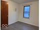 A simple empty room with white walls, gray flooring, and a window providing natural light at 1900 E Purdue Rd, Muncie, IN 47303