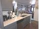 View of the kitchen island with a white countertop, gray cabinets, and stainless steel dishwasher, with an open living area at 2121 Grenville St # Apt 2A, Carmel, IN 46032