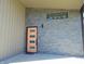 Close-up of a modern, orange front door with sleek sidelights, complemented by the gray stone facade at 2528 Carrollton Ave, Indianapolis, IN 46205