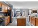 Modern kitchen with wood cabinets, a stainless steel refrigerator, and an island, flowing into the dining area at 3322 Paisley Pointe, Whitestown, IN 46075