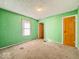 Green bedroom with window and orange door, worn and in need of repair at 3455 Hillside Ave, Indianapolis, IN 46218