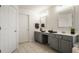 Bright bathroom features dual sinks with modern fixtures, gray cabinets, and neutral tile flooring at 3880 Heathfield Ct, Zionsville, IN 46077