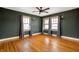Empty room with hardwood floors, two windows, neutral curtains, and dark-painted walls at 4212 Broadway St, Indianapolis, IN 46205