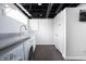Basement laundry room featuring modern washer/dryer, utility sink, and a black open beam ceiling at 4212 Broadway St, Indianapolis, IN 46205