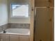 A bathtub and glass shower, with gray tile and neutral paint at 457 Prince Dr, Greenwood, IN 46142