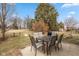 View of a concrete patio, featuring a table with six chairs, and a large tree in the fenced yard at 4704 Whitview Ln, Indianapolis, IN 46237