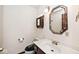 Bathroom features a toilet, sink, vanity with framed mirror, and decorative lights at 5519 Fall Creek Rd, Indianapolis, IN 46220