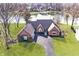 Aerial view of a waterfront home with a red brick exterior, well-manicured lawn, and a long driveway leading to the house at 5519 Fall Creek Rd, Indianapolis, IN 46220