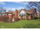 A beautifully landscaped backyard featuring a partially covered deck, brick chimney, and lush green lawn at 5519 Fall Creek Rd, Indianapolis, IN 46220