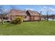 View of the backyard of a well-maintained home with lush green lawn, mature trees, and serene waters in the background at 5519 Fall Creek Rd, Indianapolis, IN 46220