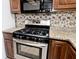 Stainless steel kitchen stove with granite countertops and floral wallpaper backsplash at 5519 Fall Creek Rd, Indianapolis, IN 46220