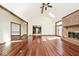 Open-concept living room with hardwood floors, vaulted ceilings, a brick fireplace, and kitchen access at 5519 Fall Creek Rd, Indianapolis, IN 46220