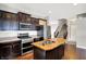 Well-equipped kitchen features wood island, stainless steel appliances, dark cabinetry, and a view of staircase at 61 Larimar Way, Whiteland, IN 46184