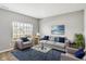 Bright living room featuring a large window, neutral walls, gray seating, blue accents, and a glass coffee table at 61 Larimar Way, Whiteland, IN 46184