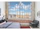 Bedroom featuring a huge window showcasing city views, complemented by exposed brick and a cozy chair at 611 N Park Ave # 414, Indianapolis, IN 46204