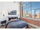 Modern bedroom with a large window, exposed brick, concrete ceiling and stylish decor at 611 N Park Ave # 414, Indianapolis, IN 46204