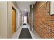 Long hallway featuring exposed brick and a neutral tile flooring pattern at 611 N Park Ave # 414, Indianapolis, IN 46204