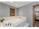 Bathroom showcasing a large soaking tub with tile surround, window, and doorway to bedroom at 7806 Ashtree Dr, Indianapolis, IN 46259