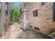 Side exterior view of a stone house showcasing a brick paved walkway and a large air conditioning unit at 906 Franklin St, Columbus, IN 47201