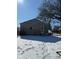 A rustic garage is shown on a sunny winter day, with a snowy yard and bare trees in the background at 911 W 3Rd St, Anderson, IN 46016