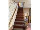 Carpeted stairs with wooden railings and decorative wallpaper, adding character to the home's interior at 911 W 3Rd St, Anderson, IN 46016