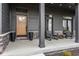 Welcoming front porch with dark siding, wooden front door, seating area and stylish decor at 1225 Amberley Way, Westfield, IN 46074