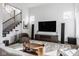 Open-concept living room with modern staircase, large TV, and stylish decor at 1225 Amberley Way, Westfield, IN 46074
