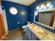 Bright blue bathroom showcasing double sinks, octagonal window, and neutral flooring at 130 Hanover Dr, Morristown, IN 46161