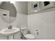 Well-lit half bath features a pedestal sink, tiled walls, modern toilet, and decorative artwork at 13610 Grand Abbey Way, Fishers, IN 46037
