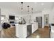 Open concept kitchen with white island, stainless steel appliances, and view of living room and staircase at 13622 Grand Abbey Way, Fishers, IN 46037