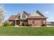 Charming brick two-story home with manicured lawn and mature tree against a clear blue sky at 2838 Violet W Ct, Columbus, IN 47201