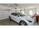 Clean and organized two car garage with white walls and concrete floor containing a white electric vehicle at 2838 Violet W Ct, Columbus, IN 47201
