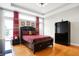 Bright bedroom boasts tray ceiling, hardwood floors, large windows with red drapes, and a modern closet at 3924 Bear Creek Way, Carmel, IN 46074