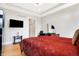 Airy bedroom boasts tray ceiling, hardwood floors, large windows, and a dark wood entertainment center with a flat screen TV at 3924 Bear Creek Way, Carmel, IN 46074
