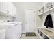 Well-lit laundry room featuring white washer and dryer, cabinets, and a mudroom area with bench and hooks at 3924 Bear Creek Way, Carmel, IN 46074