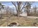 Backyard featuring a fire pit, detached garage, large tree, fence and bare grass at 4249 Dubarry Rd, Indianapolis, IN 46226